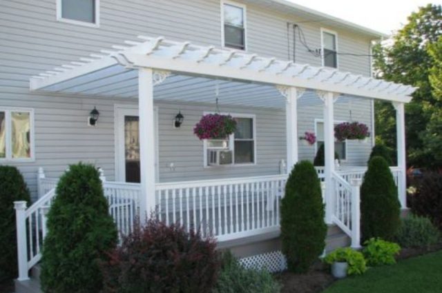 white vinyl attached pergola and railing around a back deck on a house