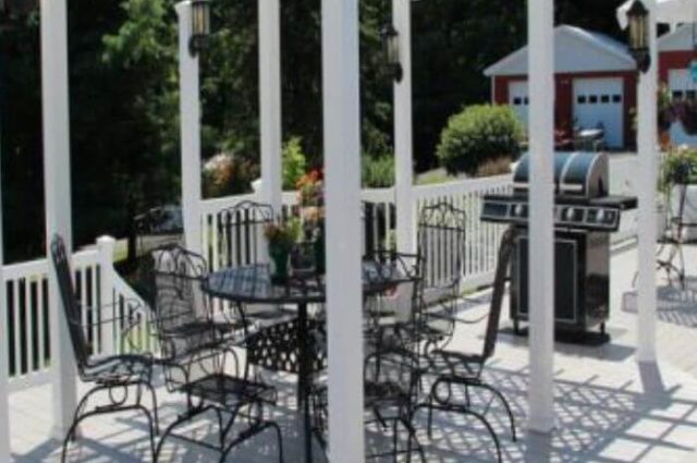 white vinyl pergola in a deck area over table and chairs