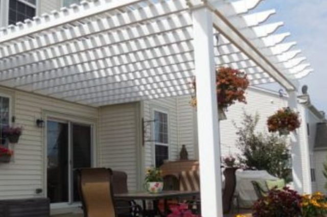 white vinyl pergola attached to a house and over a deck area