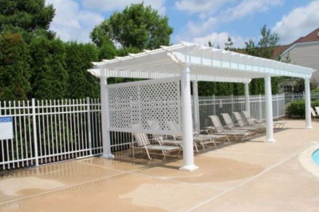 white freestanding vinyl pergola with rounded posts beside an outdoor pool