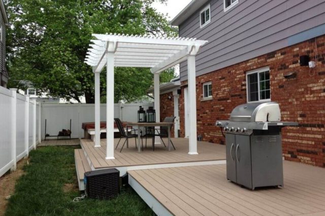 white vinyl free standing pergola over a tan vinyl deck in the backyard