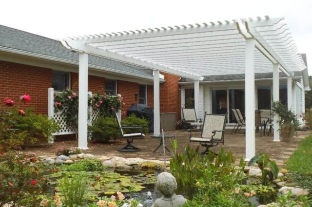 detached vinyl pergola in white with square posts over a backyard living area
