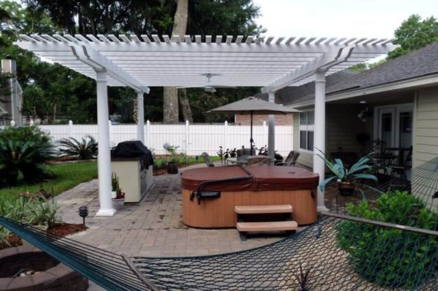 white pergola attached to a house over a hot tub over a patio