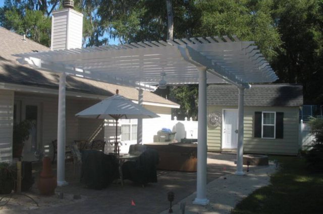 white vinyl pergola attached to a home and over a backyard patio area