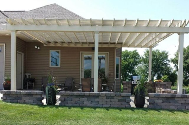 almond vinyl pergola attached to brick home and over an outdoor patio