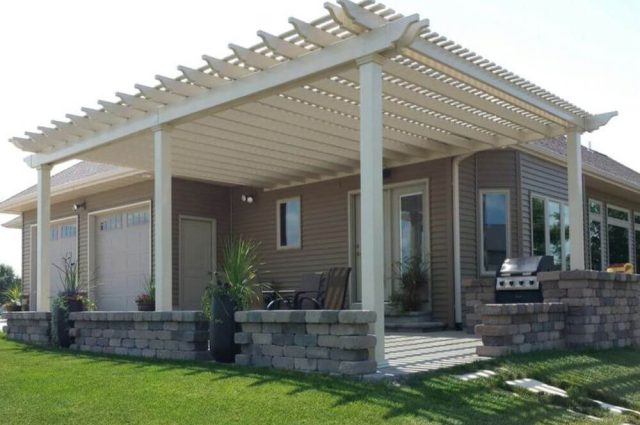 brick home with two car garage that has a attached pergola over a new patio