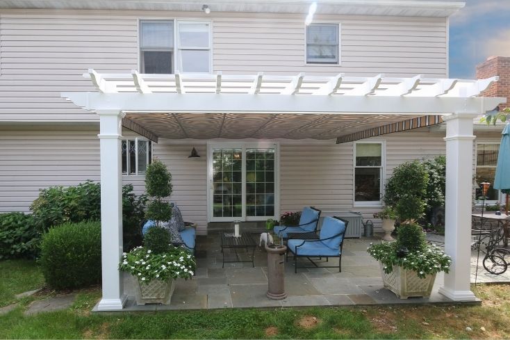 Patio and seating area shaded by white attached outdoor pergola