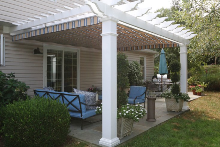 Attached vinyl backyard pergola with canopy and backyard furniture