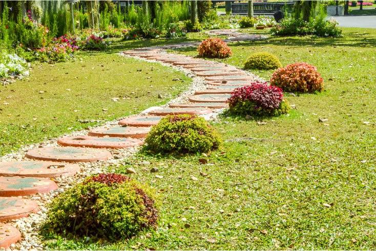 A stone pathway pictured with green grass and florals makes a great DIY makeover option.