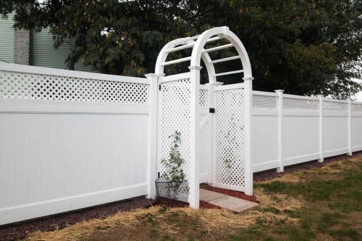 vinyl arched arbor show in backyard with attached vinyl fencing