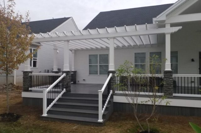 white and black vinyl railing around a front porch with a white pergola over part of it