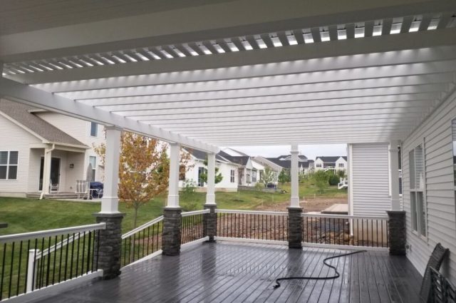 white vinyl pergola over a front porch and with square posts that have stones on them