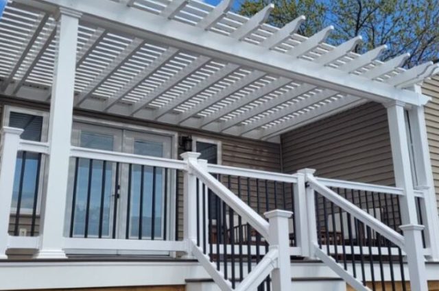 white vinyl railing around steps leading up to two story deck with white pergola over the top