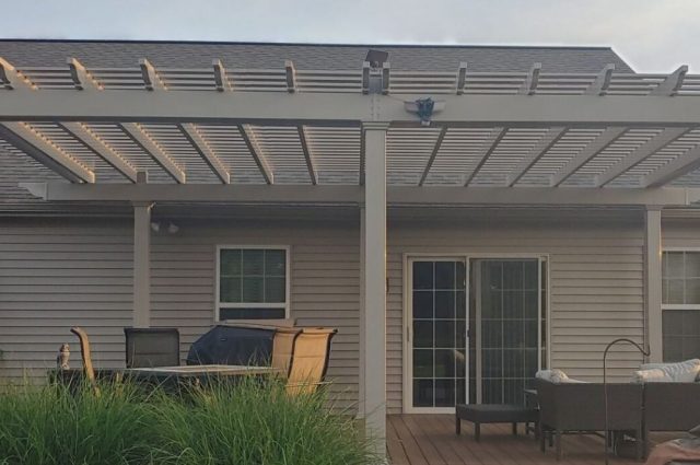 tan wall mounted pergola over a first floor deck behind a home