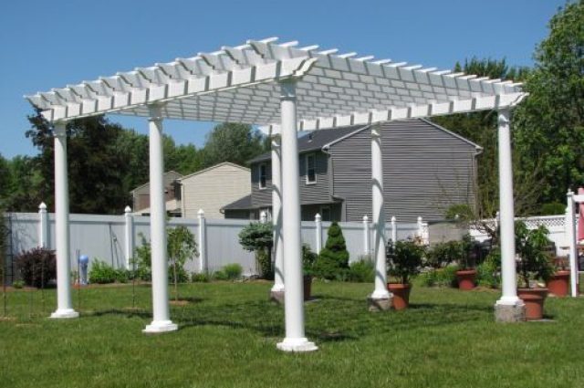 white vinyl free-standing pergola located in syracuse new york backyard and fenced in with landscaping